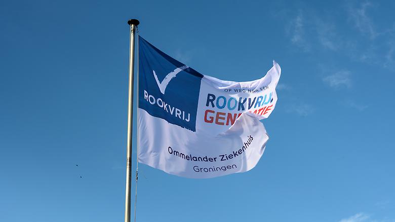  Een vlag met daarop de tekst 'Rookvrij' en 'Op weg naar een rookvrije generatie' met het logo van het Ommelander Ziekenhuis Groningen