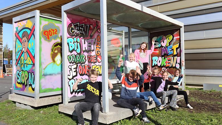  Kinderen zitten in de rookabri op het terrein van het Ommelander Ziekenhuis Groningen dat versierd is met graffiti, met teksten over stoppen met roken