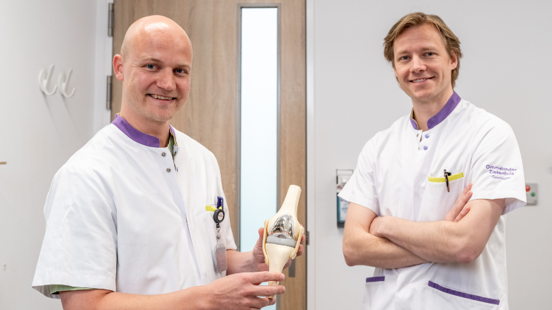 Twee specialisten houden houden een knieprothese vast